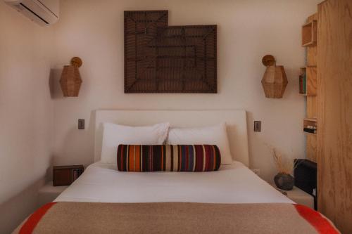 a bedroom with a white bed with a striped pillow at Entire Private Boutique Motel w Courtyard and Sauna in Marfa