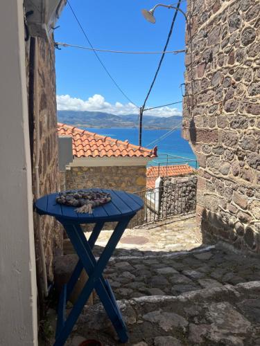 a blue table in a alley with a view of the ocean at Castellum ac Mare in Mithymna