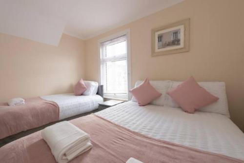 ein Schlafzimmer mit zwei Betten und einem Fenster in der Unterkunft Lovely 2 Bed House in Grays 4 Separate Beds in Grays Thurrock