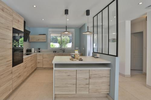 a kitchen with wooden cabinets and a counter top at Villa Familiale Proche Plage & Forêt avec Piscine Privée à Jard sur Mer in Jard-sur-Mer