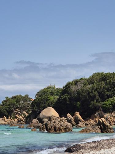 a beach with a large rock in the water at Appartement Neuf Grande Terrasse AGOSTA PLAGE in Albitreccia