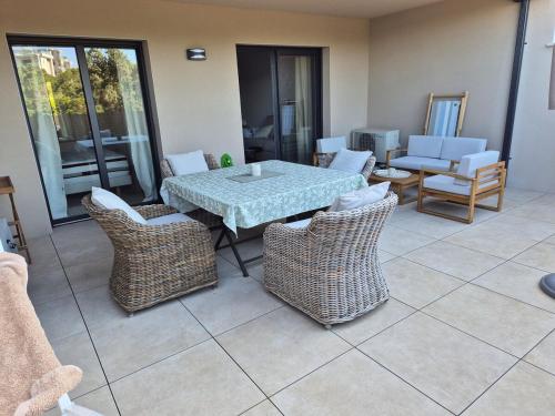 a patio with a table and wicker chairs at Appartement Neuf Grande Terrasse AGOSTA PLAGE in Albitreccia