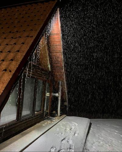 a window of a building with snow on it at Căbănuțele de lângă râu in Păucineşti