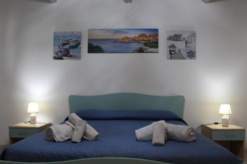 a bedroom with a blue bed with three pictures on the wall at Domo Marzellinu in Orosei