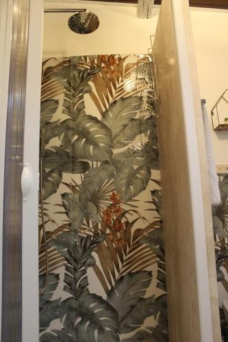 a bathroom with a green plant wallpaper on the wall at Domo Marzellinu in Orosei