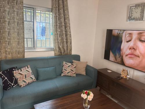 ein Wohnzimmer mit einem blauen Sofa und einem Fernseher in der Unterkunft Guest house in Sanyang