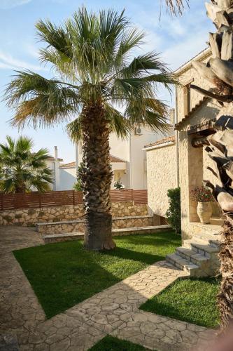 a palm tree in front of a house at Casa Livia - Secluded Stone Villa with Private Pool and Panoramic Sea Views in Tragaki