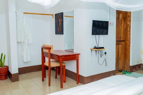 a room with a table and a chair and a tv at Glacier View Lodge in Moshi