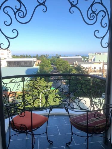 a balcony with two chairs and a view of a city at LA MER Homestay Quynhon in Quy Nhon