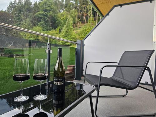 two glasses of wine and a chair on a glass table at Pfalztraum Fewo's in Bruchweiler-Bärenbach