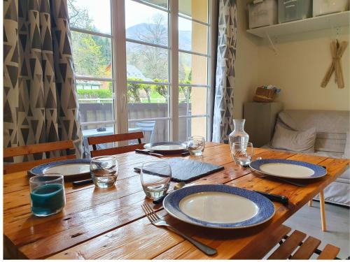 une table en bois avec des assiettes et des verres dans l'établissement La Pause Bourboulienne Appartement RDC avec balcon, à La Bourboule