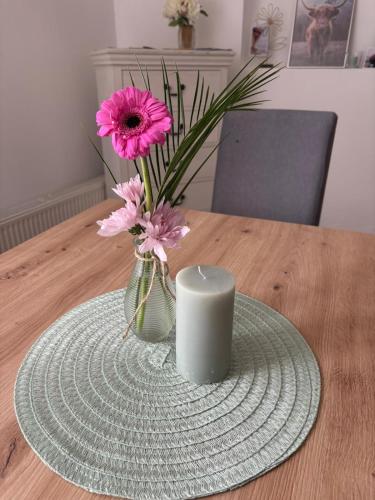 a vase with a pink flower and a candle on a table at Dorfwohnzimmer Apartment in Roggendorf