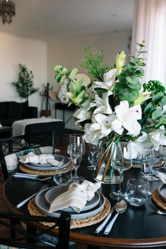 a black table with plates and vases with white flowers at Little Luxe Retreat in Findon