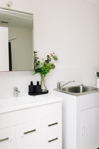 a white kitchen with a sink and a mirror at Little Luxe Retreat in Findon