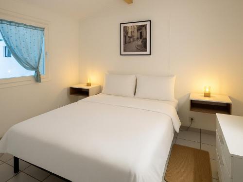 - une chambre avec un lit blanc et 2 bougies sur les tables dans l'établissement Pavillon Refait à Neuf à Argelès-sur-Mer, Climatisé avec Wi-Fi, Terrasse et Piscine, Proche Plage - FR-1-732-82, à Argelès-sur-Mer