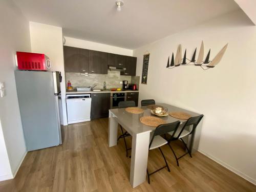 une cuisine avec une table, des chaises et un réfrigérateur dans l'établissement Appartement Neuf, Plage & Centre-Ville à Pied, à Lacanau