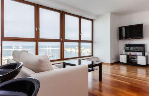 a living room with white furniture and large windows at Sea Towers Luxury Apartment in Gdynia