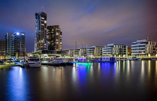 a city skyline with boats in the water at night at Sea Towers Luxury Apartment in Gdynia
