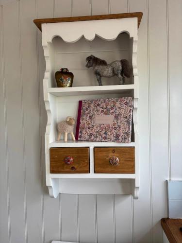 a shelf in a wall with drawers and stuffed animals at The Meadows Hut in Alvington