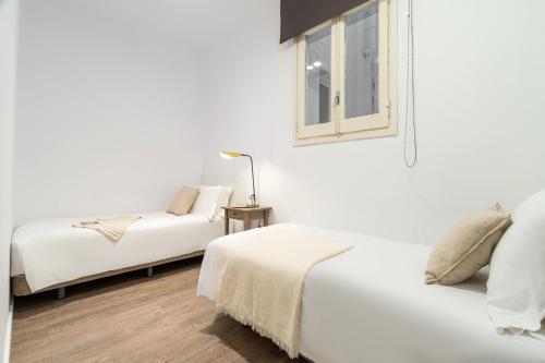 a white bedroom with two beds and a window at Aspasios Rambla Catalunya Apartments in Barcelona