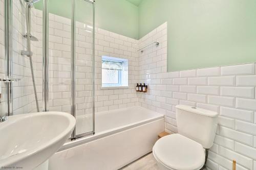 a white bathroom with a tub and a toilet and a sink at Number 5 in Margate