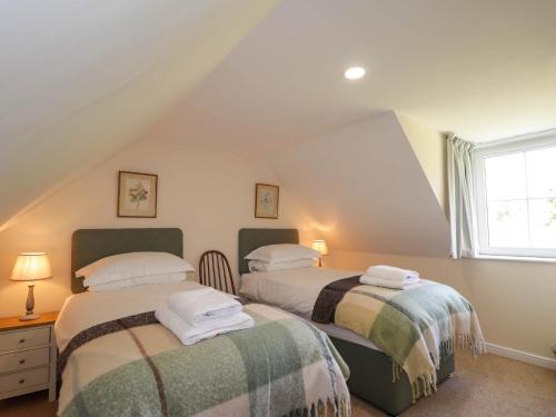 deux lits dans une chambre mansardée avec une fenêtre dans l'établissement North Cottage, à Glenelg