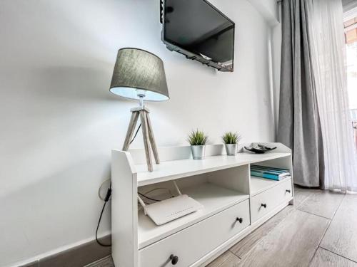 a white cabinet with a lamp and a tv on a wall at Reformed studio apartment in central Nerja 3K in Nerja