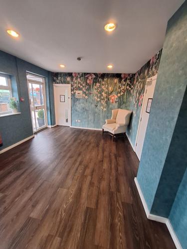 an empty living room with a chair and a wall with flowers at Stockwood Hotel - Luton Airport in Luton