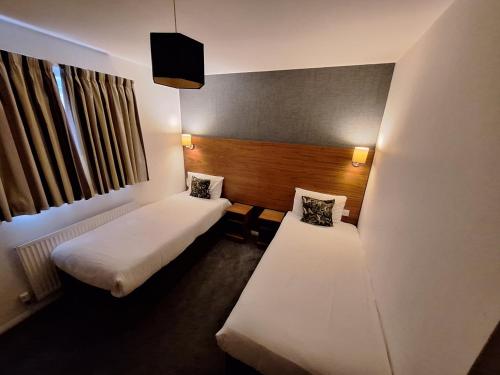 a hotel room with two beds and a window at Stockwood Hotel - Luton Airport in Luton