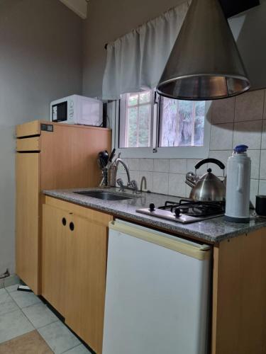 a kitchen with a stove and a sink with a tea kettle at Cabañas Posada del Sol in Junín