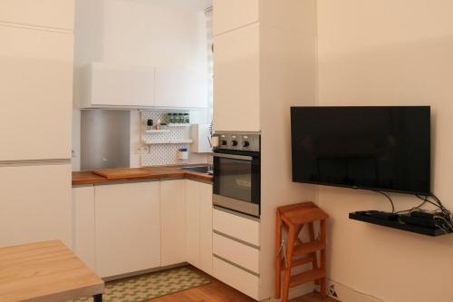 une cuisine avec des armoires blanches et une télévision à écran plat dans l'établissement Beautiful cocoon of love - near park, à Paris