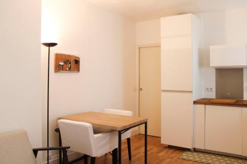 - une cuisine avec une table en bois et des chaises blanches dans l'établissement Beautiful cocoon of love - near park, à Paris