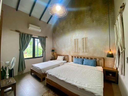 a bedroom with two beds and a chandelier at Nhà Lúa Homestay in Ninh Binh