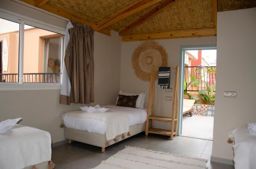 a bedroom with two beds and a balcony at harmony surf lodge in Taghazout