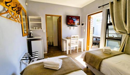 a room with two beds and a desk in it at Tiende Laan Bed & Breakfast and Self-Catering in Walvis Bay