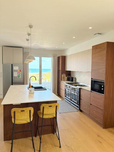 une cuisine avec un grand îlot et deux tabourets de bar jaunes dans l'établissement Bidart - Modern house - Ocean view - beach, à Bidart