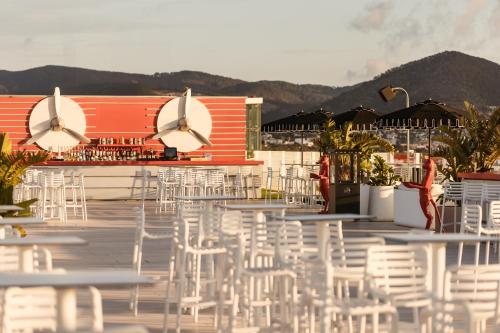 a group of white chairs and tables on a deck at Ushuaïa Ibiza Beach Hotel - Adults Only - Club Entrance Included in Playa d'en Bossa