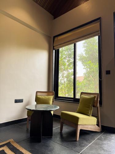 a room with two chairs and a table and a window at The Bali House in Bhopal