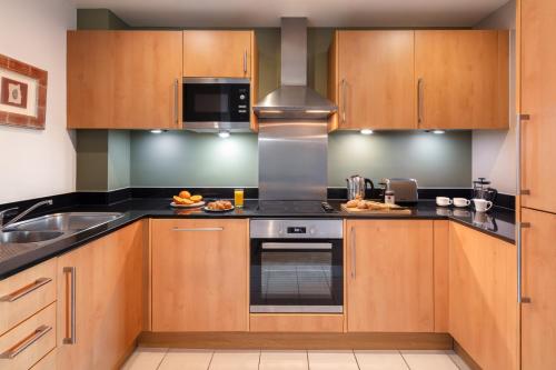 a kitchen with wooden cabinets and a stove top oven at Marlin Apartments London Bridge - Empire Square in London