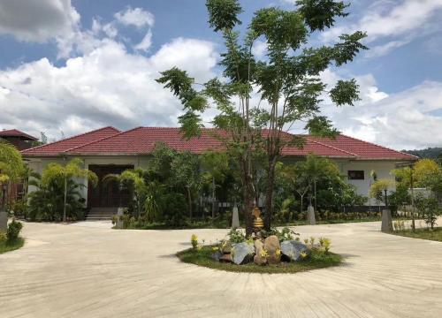 ein Haus mit einem Baum in der Mitte einer Auffahrt in der Unterkunft Diamond Villas in Ban Phang Phrao