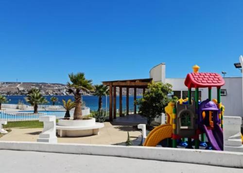 a playground in front of a swimming pool with a playground at Hermoso departamento en la playa in Coquimbo