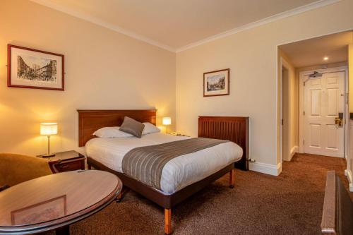 a hotel room with a bed and a table at Hollins Hall Hotel, Golf & Country Club in Bradford