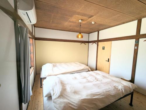 two beds in a small room with wooden ceilings at Guesthouse giwa - Vacation STAY 23190v in Mishima