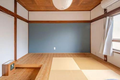 an empty room with a blue wall and wooden floors at Guesthouse giwa - Vacation STAY 23190v in Mishima