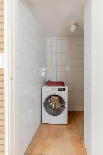a washer and dryer in a white tiled laundry room at Duin & Daal in Helvoirt