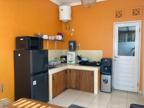 a kitchen with a black refrigerator and an orange wall at House Shizen I in Uluwatu