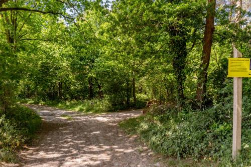 a dirt road through a forest with a yellow sign at Duin & Daal in Helvoirt
