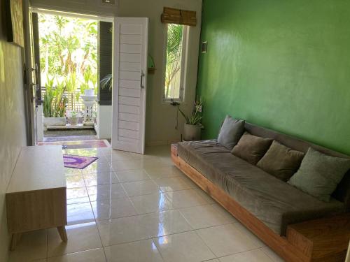 a living room with a couch and a green wall at House Shizen I in Uluwatu