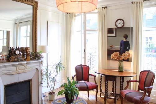 un salon avec une table et des chaises et une cheminée dans l'établissement Family duplex - with balcony, à Paris