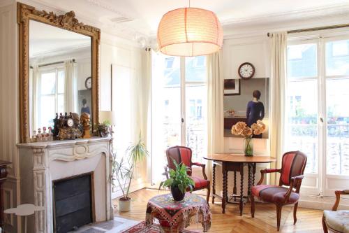 - un salon avec une cheminée, une table et un miroir dans l'établissement Family duplex - with balcony, à Paris